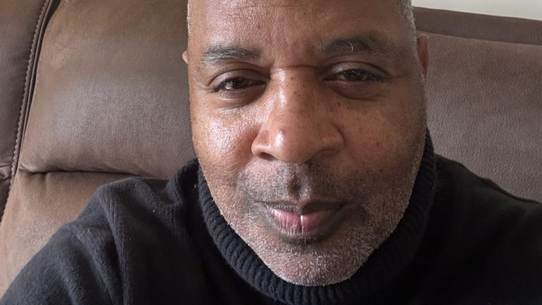Close-up portrait of man with gray beard wearing black turtleneck sweater indoors